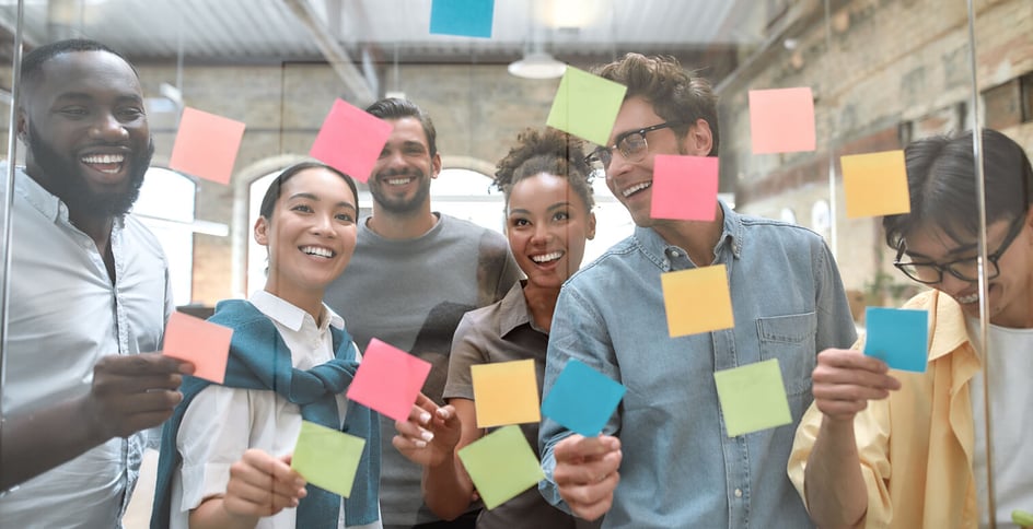 Happy coworkers sharing ideas with post-it notes.